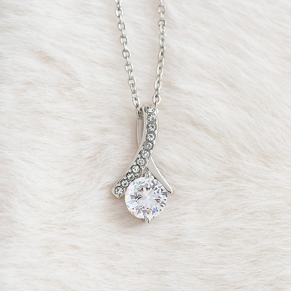 Close-up of the Alluring Beauty ribbon pendant and round cubic zirconia in white gold finish