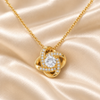 Gold Forever Yours Love Knot necklace shown close up on ivory satin