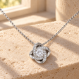Silver Forever Yours Love Knot necklace shown close up on ivory stone in warm window light
