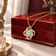 Gold Forever Yours Love Knot necklace draped over a closed mahogany box on a dressing table